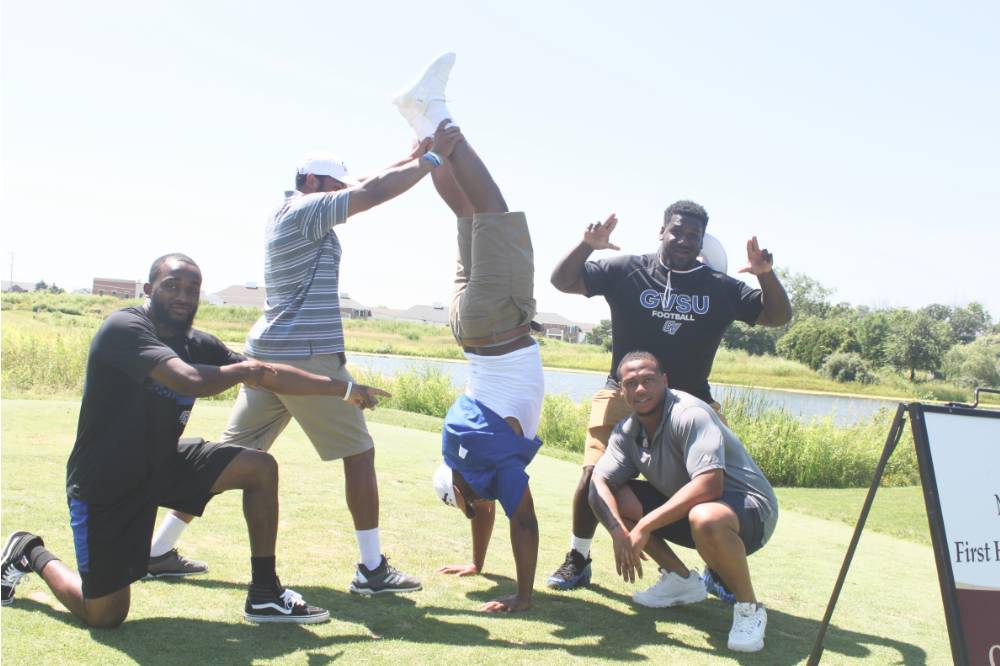 5 men take a funny group picture on the course